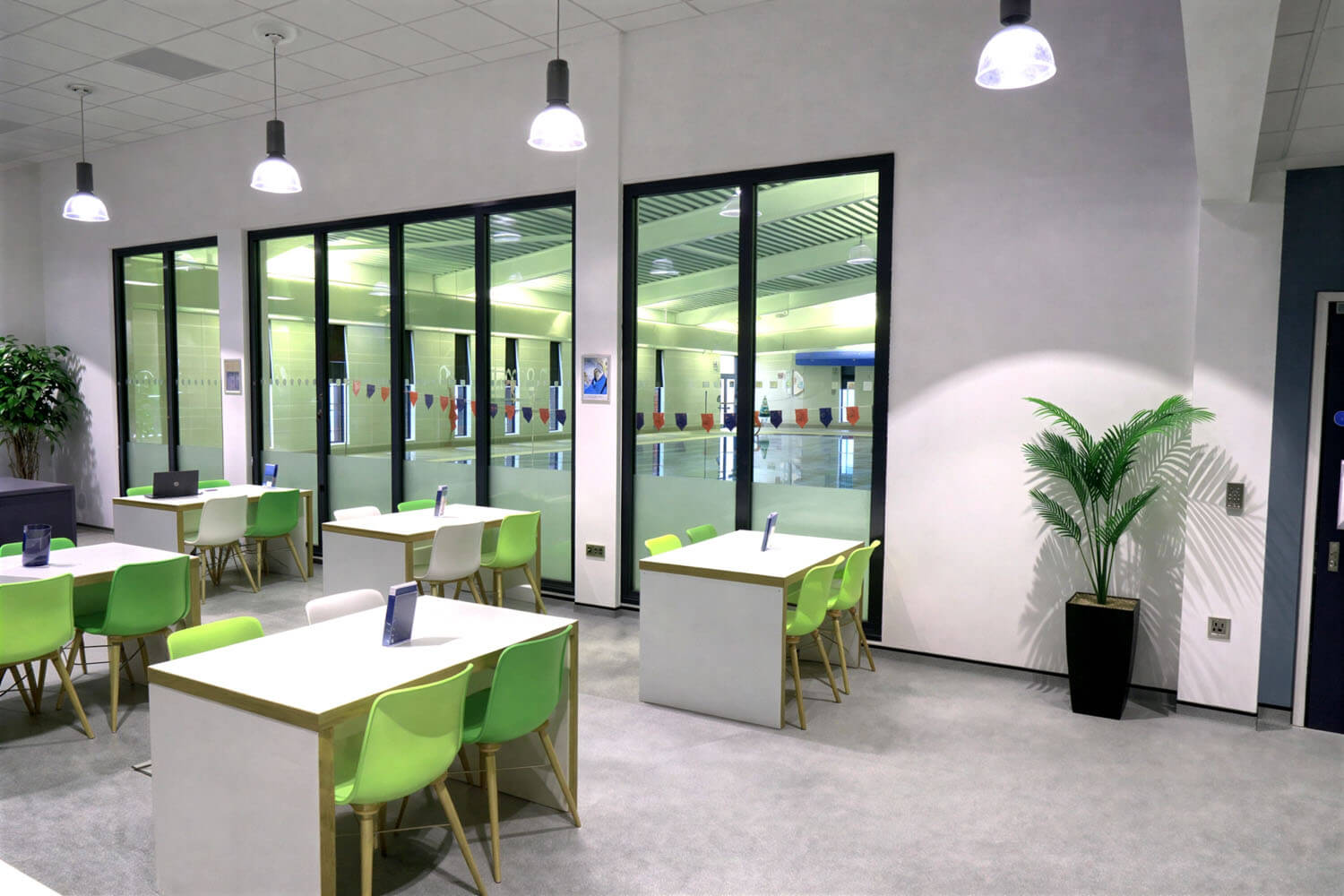 Café seating beside the pool hall, with glazing giving a view through to the water at Ripon