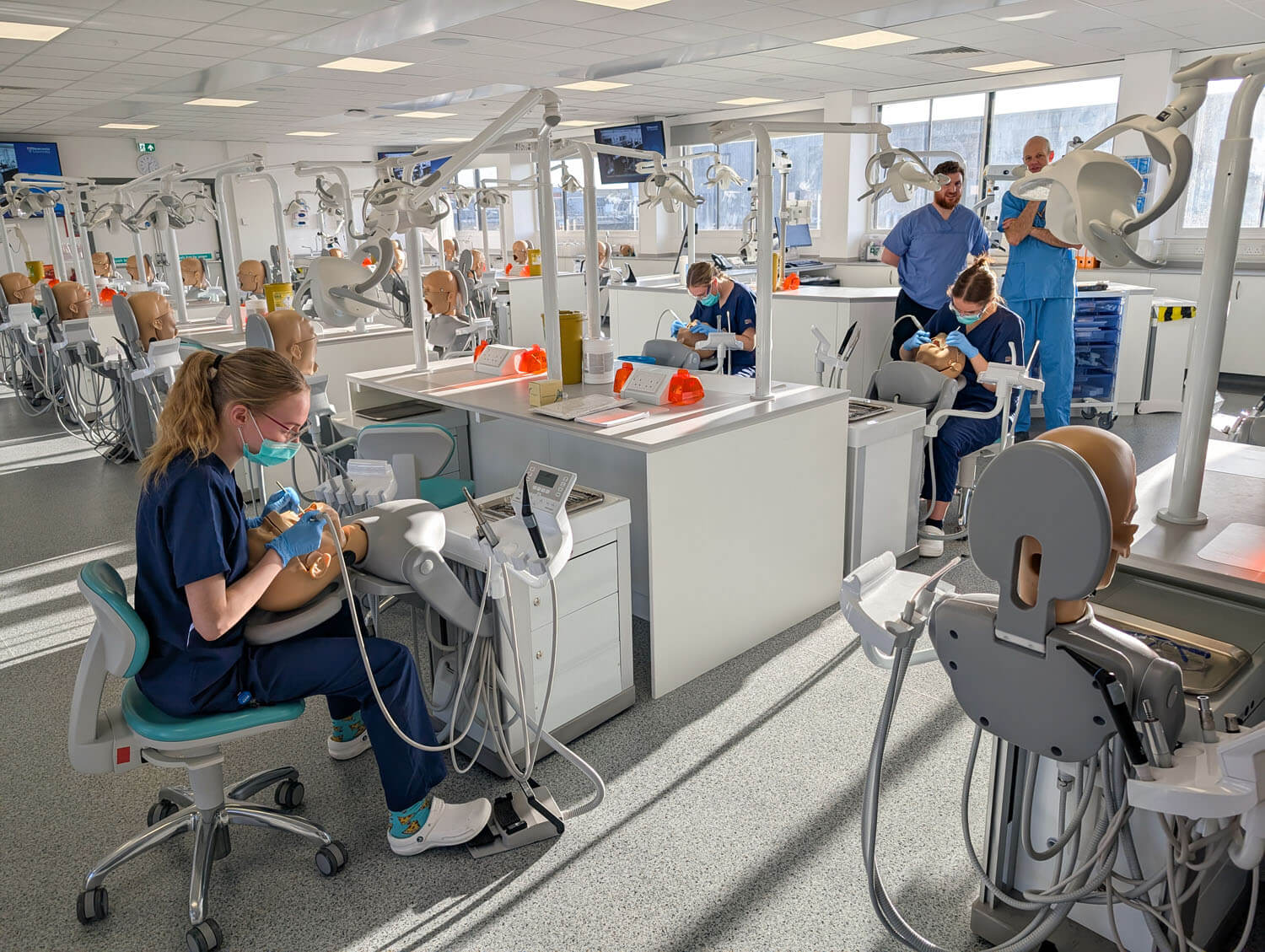 Specialist laboratory showing specialist dental training equipment and controlled environment engineering with students working at simulation bays